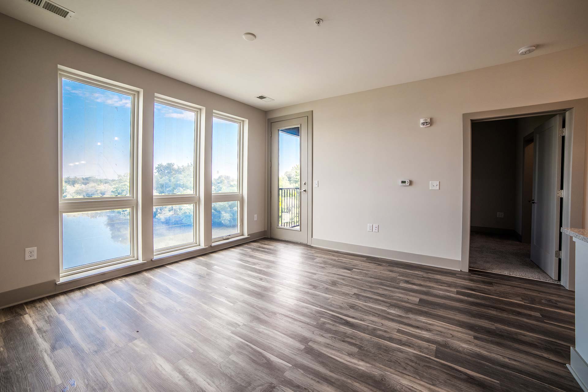an empty room with hardwood floors and large windows at The River House